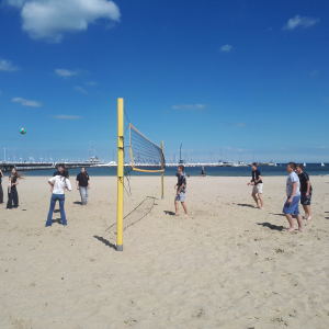 Grupa uczniów na plaży podczas gry w siatkówkę. Kliknięcie w zdjęcie spowoduje powiększenie do oryginalnego rozmiaru.