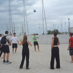 Grupa uczniów na plaży podczas odbijania piłki. Kliknięcie w zdjęcie spowoduje powiększenie do oryginalnego rozmiaru.