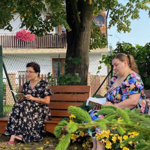Dwie nauczycielki języka polskiego siedzą na ławeczkach pod lipą.  Kliknięcie w zdjęcie spowoduje powiększenie do oryginalnego rozmiaru.