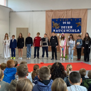Uczniowie podczas występu stoją na scenie. Kliknięcie w zdjęcie spowoduje powiększenie do oryginalnego rozmiaru.