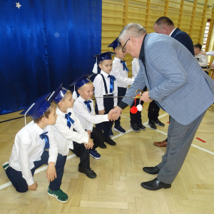 Pan dyrektor pasuje ucznia klasy pierwszej. Kliknięcie w zdjęcie spowoduje powiększenie do oryginalnego rozmiaru.