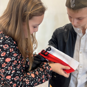 Uczeń i uczennica podczas akademii. Kliknięcie w zdjęcie spowoduje powiększenie do oryginalnego rozmiaru.