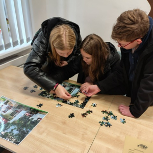 Troje uczniów podczas układania puzzli. Kliknięcie w zdjęcie spowoduje powiększenie do oryginalnego rozmiaru.