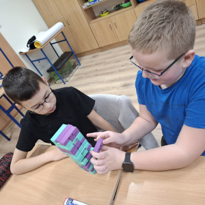 Dwoje uczniów układa wieżę jengę. Kliknięcie w zdjęcie spowoduje powiększenie do oryginalnego rozmiaru.