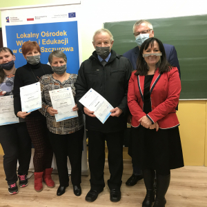 Uczestnicy zajęć podczas wręczenia certyfikatów ukończenia. W tle baner projektu. . Kliknięcie na zdjęcie spowoduje jego powiększenie do oryginalnego rozmiaru.